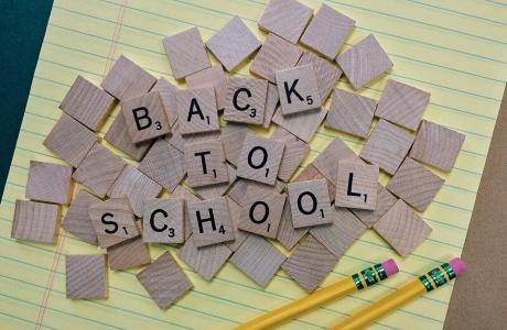 small wood squares spelling out Back To School on yellow lined paper with two pencils