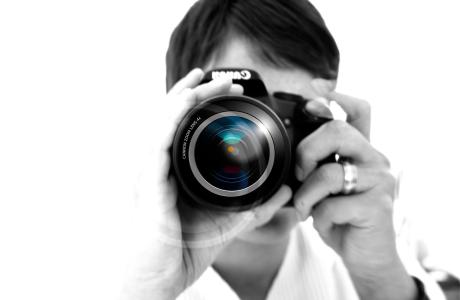 Black and white photo of person holding black camera taking a photo 