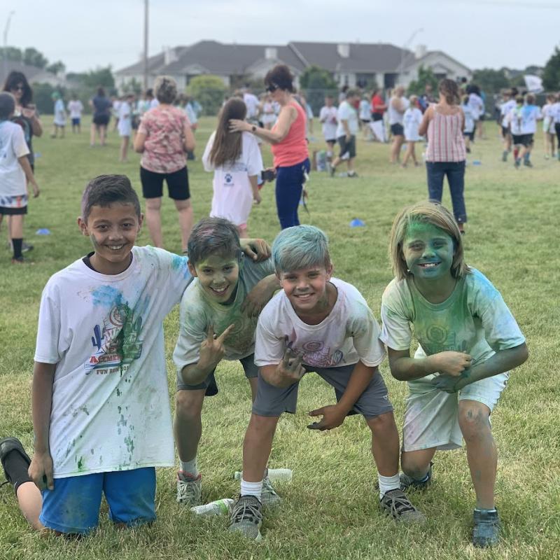 Students covered with color dust kneeling down in a grass field during the 21-22 Fun Run