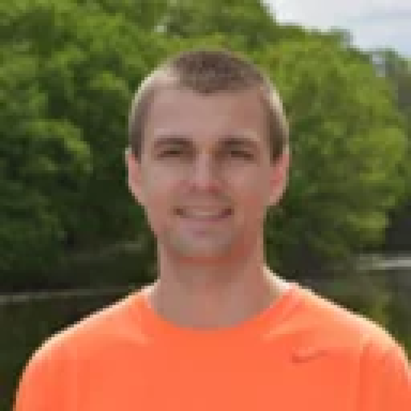 photo of Michael Rucker in front of tree wearing an orange shirt