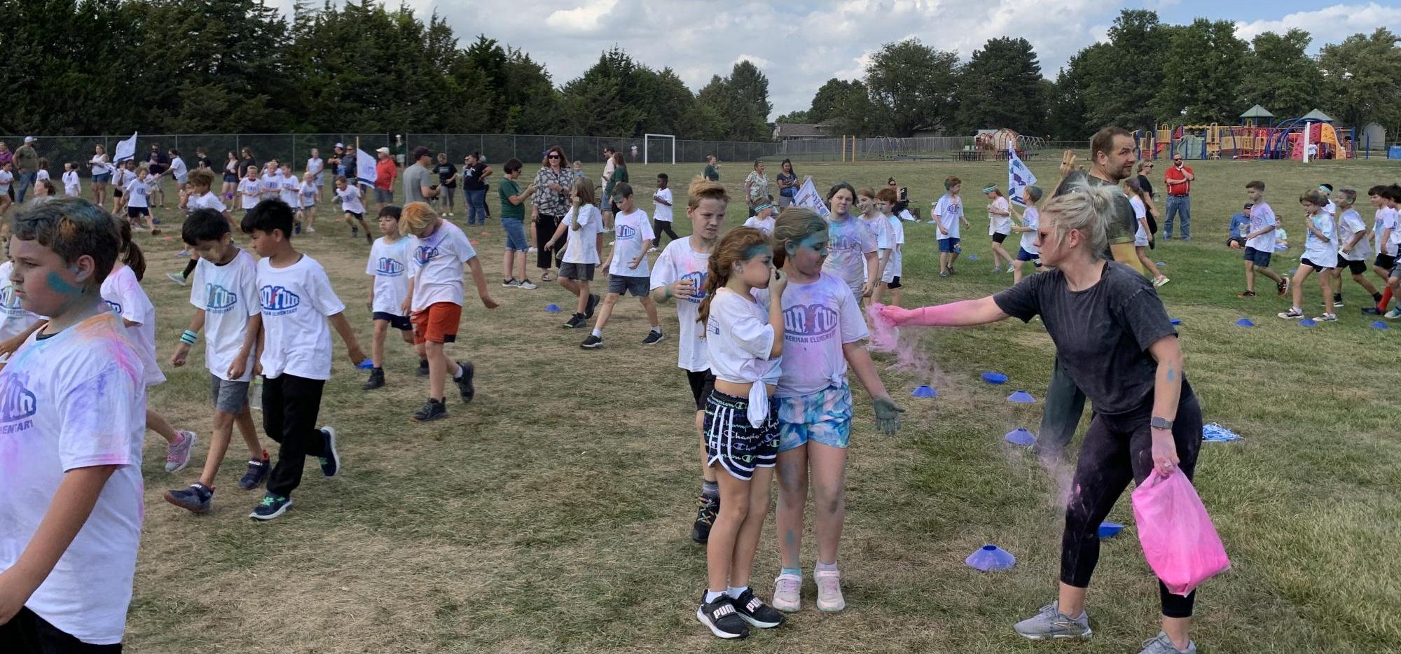Parent throwing color powder on students during the Color Fun Run