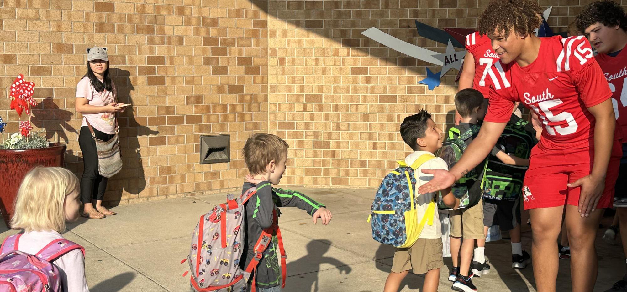 football player greeting students on first day of school