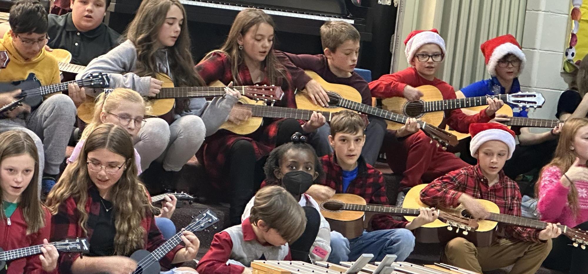 children sitting on steps playing guitars and ukeleles